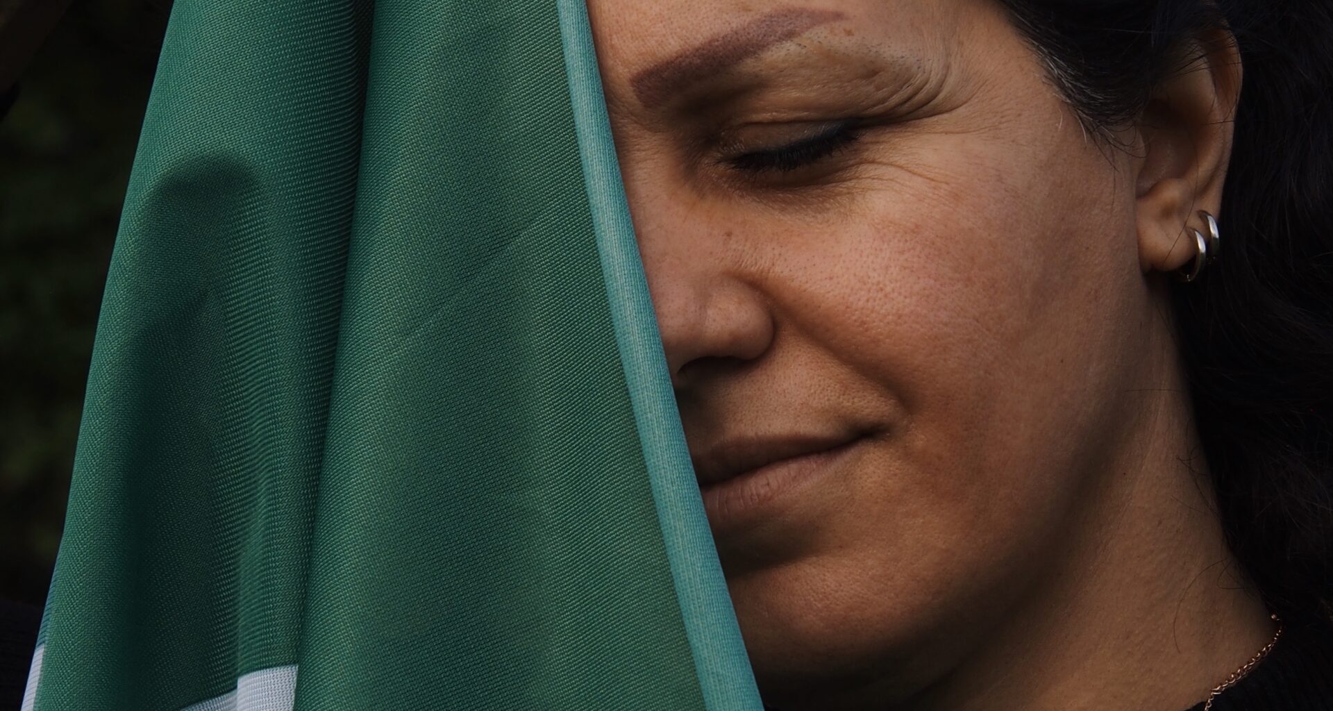 Das Bild zeigt Fariba mit einer Iran-Flagge, mit der sie zum Teil ihr Gesicht bedeckt.