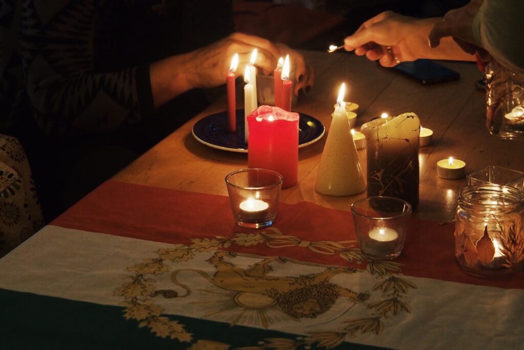 Das Bild zeigt angezündete Kerzen, die auf einem Tisch stehen.