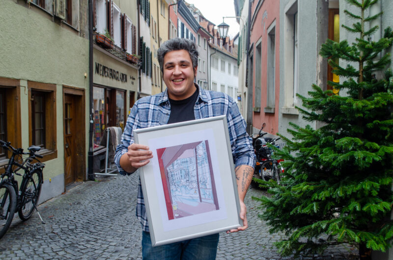 Das Bild zeigt John Singh mit dem Kunstdruck von Thilo Rothacker in Konstanz.