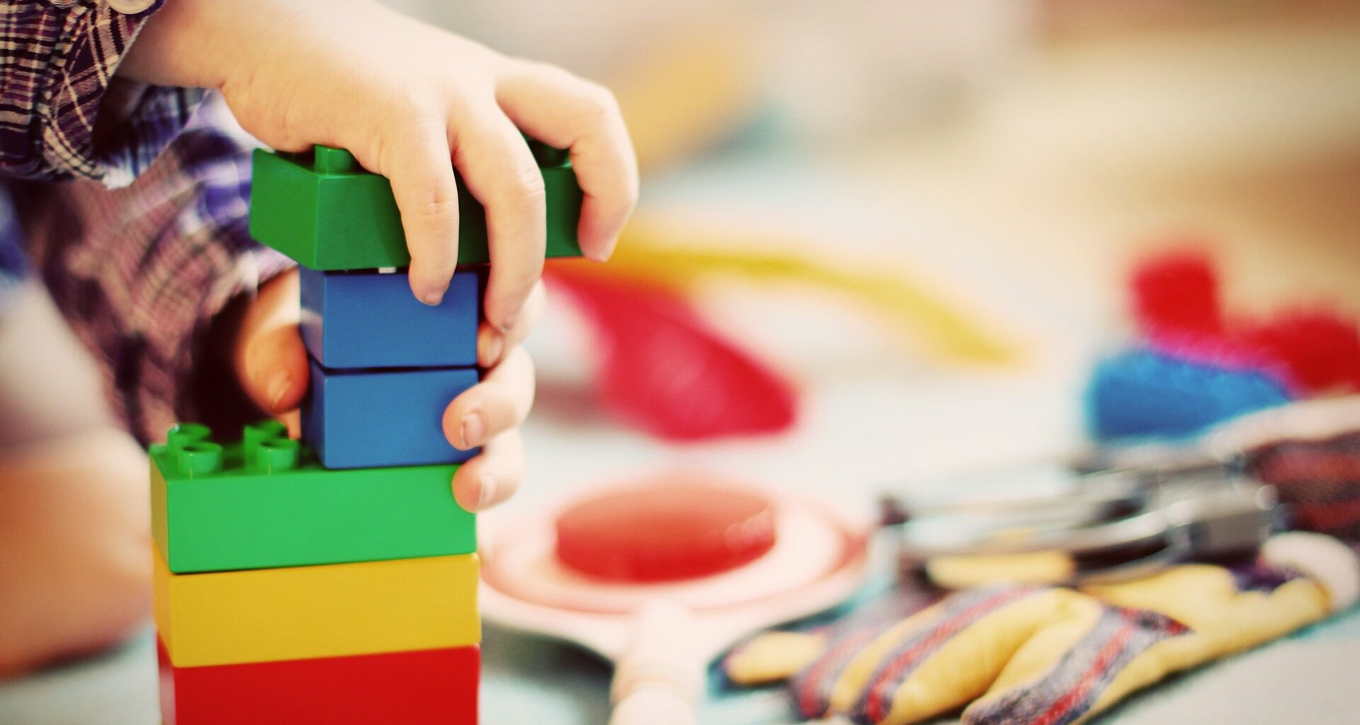 Das Foto zeigt ein Kind, das mit Holzbausteinen spielt.