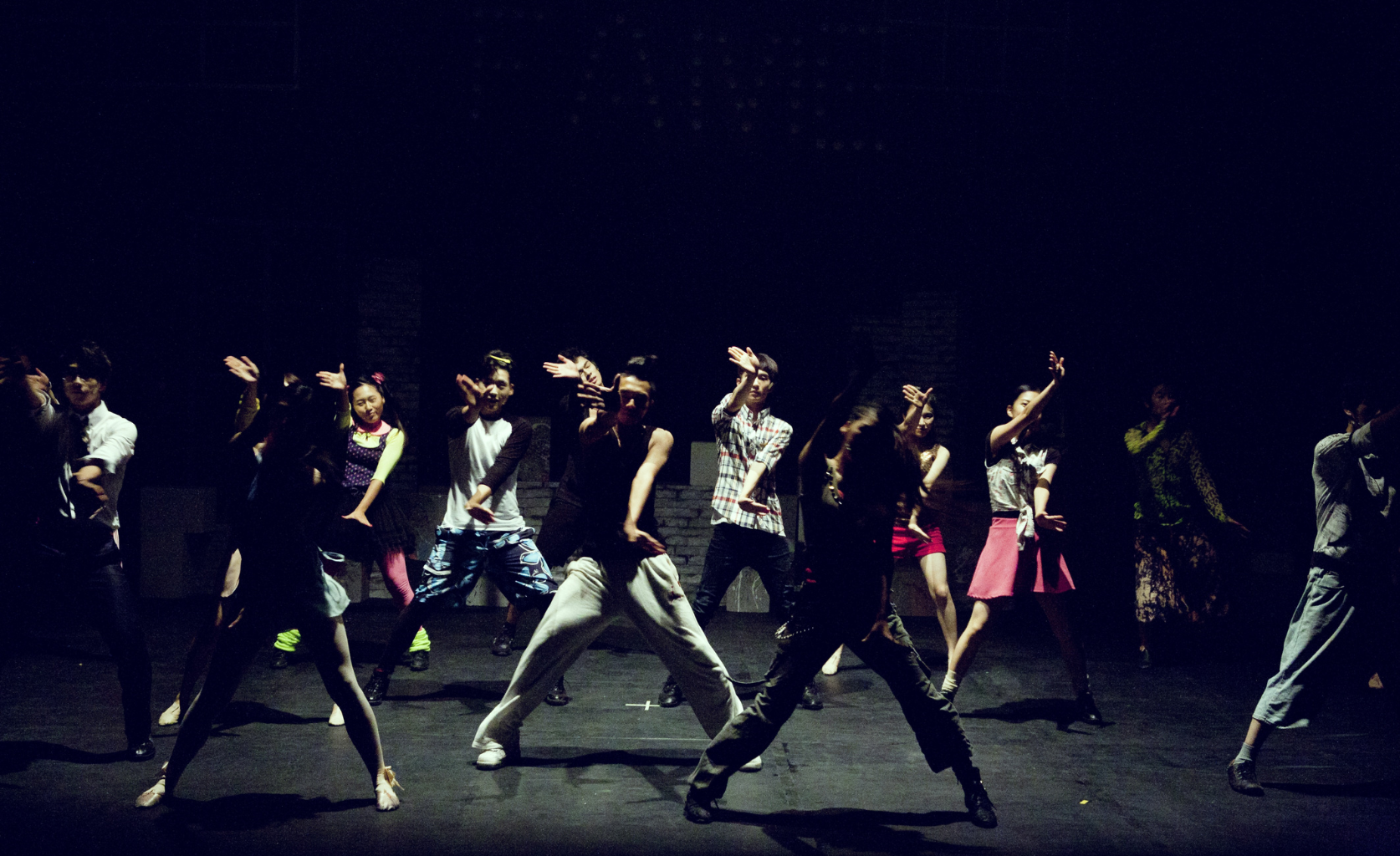 Das Bild zeigt ein großes Tanzensemble aus jungen Leuten auf einer Bühne