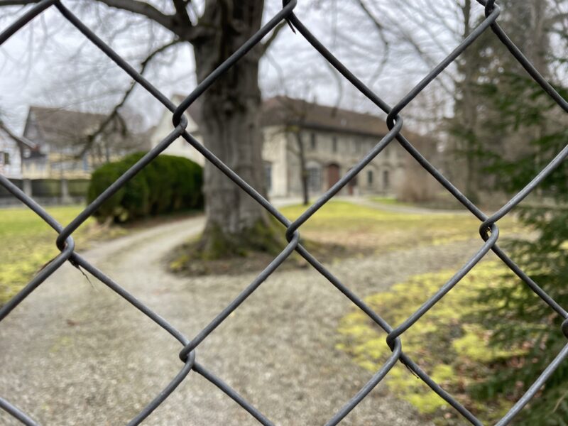 Das Foto zeigt die Remise am Schloss Gottlieben hinter einem Zaun. Das Schlossareal steht aktuell zum Verkauf.