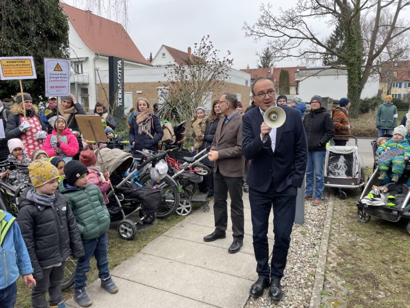 Das Foto zeigt den Konstanzer Oberbürgermeister Uli Burchardt mit einem Megafon in der Hand. Er spricht zu Demonstrant:innen, die sich gegen die Erhöhung der Kitagebühren wehren.