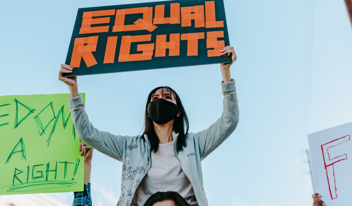 Das Bild zeigt eine Frau bei einer Demonstration mit einem Schild auf dem Equal Rights steht.