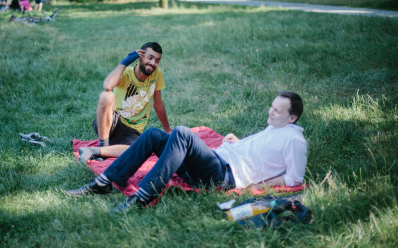Das Foto zeigt zwei Menschen auf einer Picknickdecke.