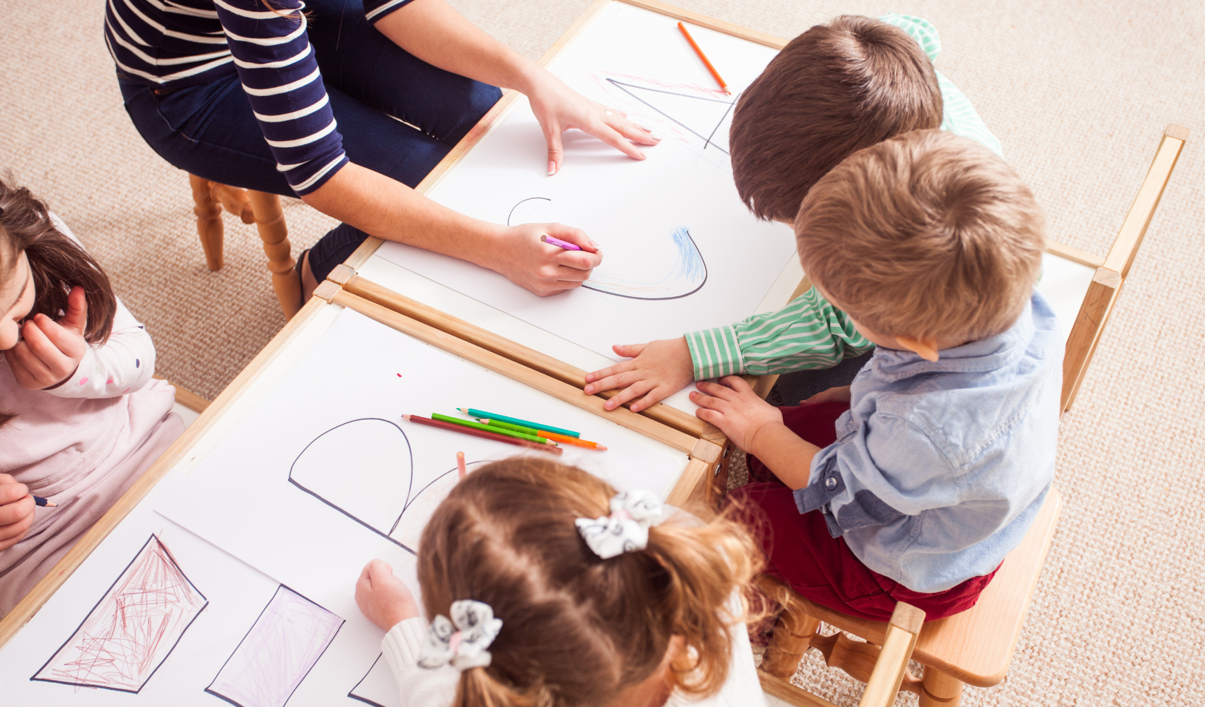 Das Foto zeigt drei Kinder in einer Kita beim Zeichnen.