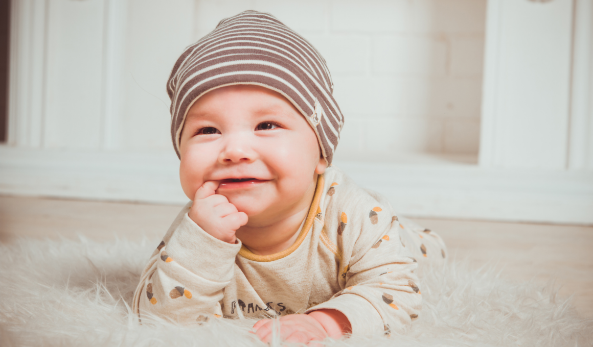 Bild eines lächelnden Babys auf einem Teppich.